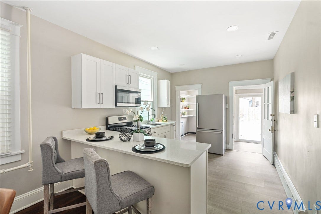 3314 Grayland Avenue, Richmond, VA 23221 Modern kitchen featuring white shaker cabinetry, stainless steel appliances, a breakfast bar with stone-finish countertops, recessed lighting, and wood-finish flooring