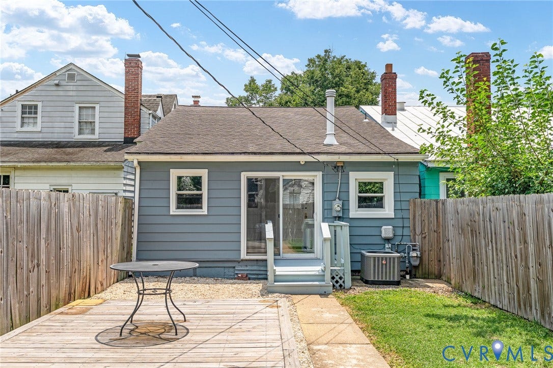 3314 Grayland Avenue, Richmond, VA 23221 Rear exterior featuring blue siding, a wooden deck, a sliding glass door, and a gravel area