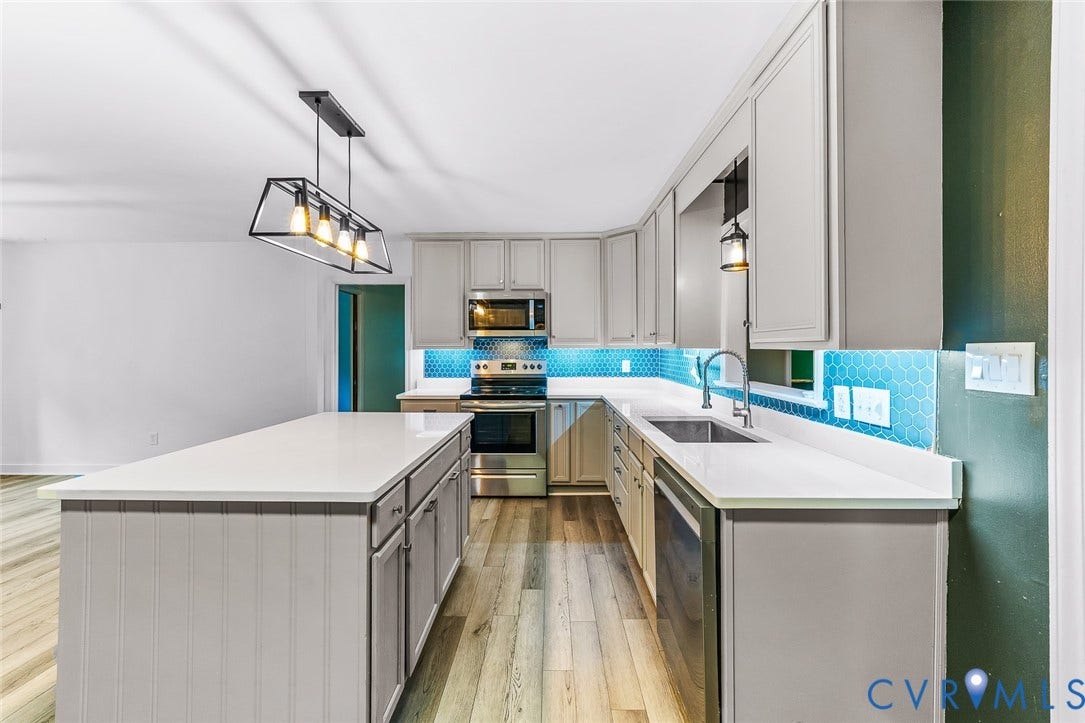 Kitchen featuring light wood-finish flooring, light gray cabinetry, and white countertops