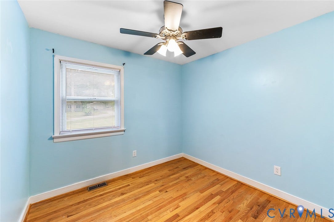 Bright interior space featuring wood-finish flooring, a ceiling fan with integrated lighting, and a window with blinds