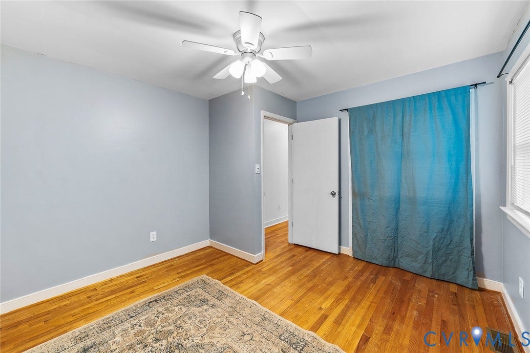 Room featuring wood-finish flooring, light blue wall paint, white baseboards, and a ceiling fan with integrated lighting