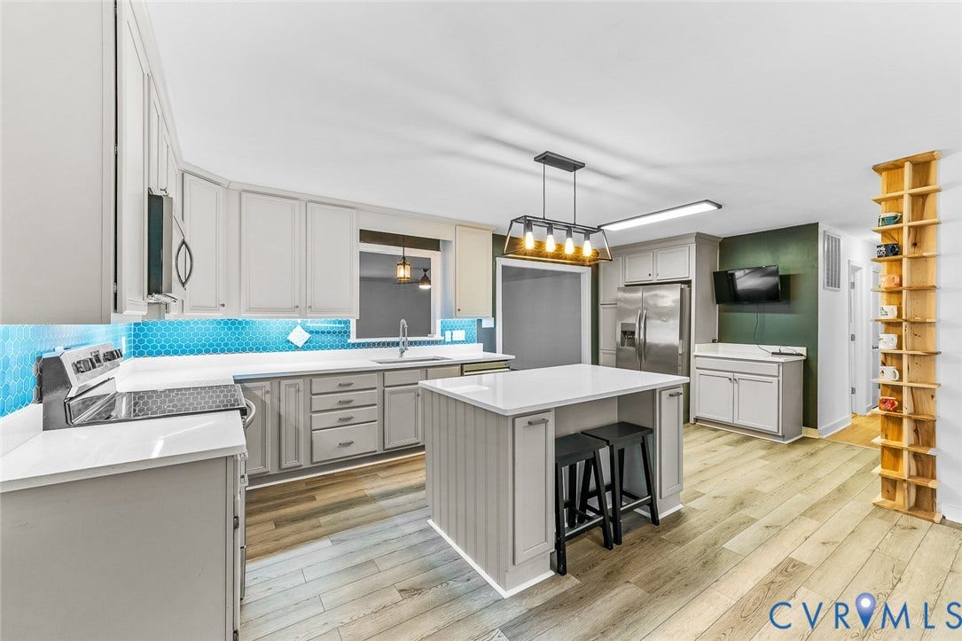 Contemporary kitchen featuring light wood-finish flooring, light grey cabinetry, white countertops, and a blue hexagonal tile backsplash