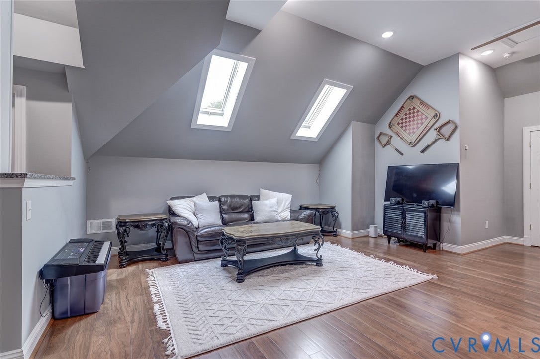 332 Rexmoor Terrace, Richmond, VA 23236 Vaulted ceiling room featuring two skylights, recessed lighting, wood-finish flooring, and a half-wall with granite-look countertop