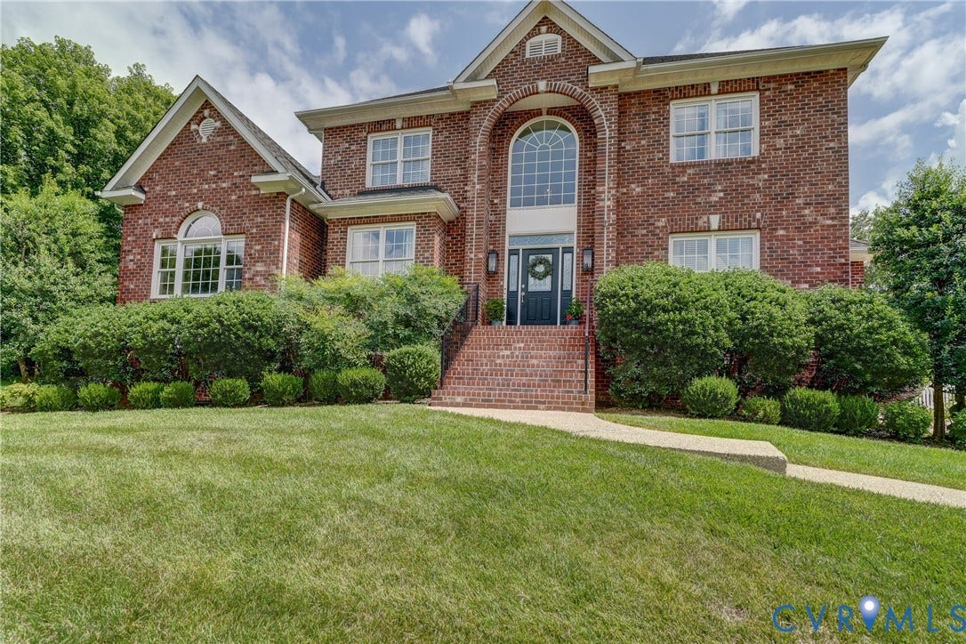 332 Rexmoor Terrace, Richmond, VA 23236 Brick facade residence featuring a prominent arched window above the main entry, a brick staircase with metal railings, a paved walkway, and established landscaping with mature shrubs and trees