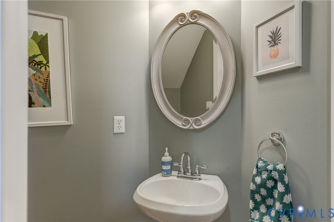332 Rexmoor Terrace, Richmond, VA 23236 Pedestal sink with chrome faucet, framed oval mirror, and light gray wall paint
