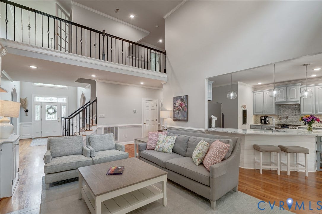 332 Rexmoor Terrace, Richmond, VA 23236 Bright living room featuring high ceilings, wood-finish flooring, a contemporary kitchen pass-through, and a decorative railing overlooking the entry