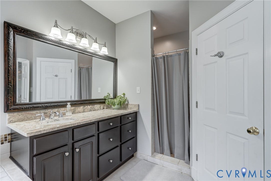 332 Rexmoor Terrace, Richmond, VA 23236 Bathroom vanity featuring a light-toned countertop, a large framed mirror, and a five-light fixture