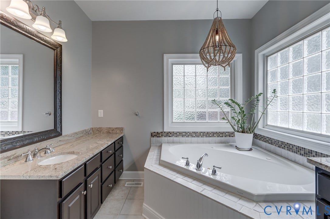 332 Rexmoor Terrace, Richmond, VA 23236 Corner soaking tub with a tiled surround, complemented by a beaded pendant light fixture