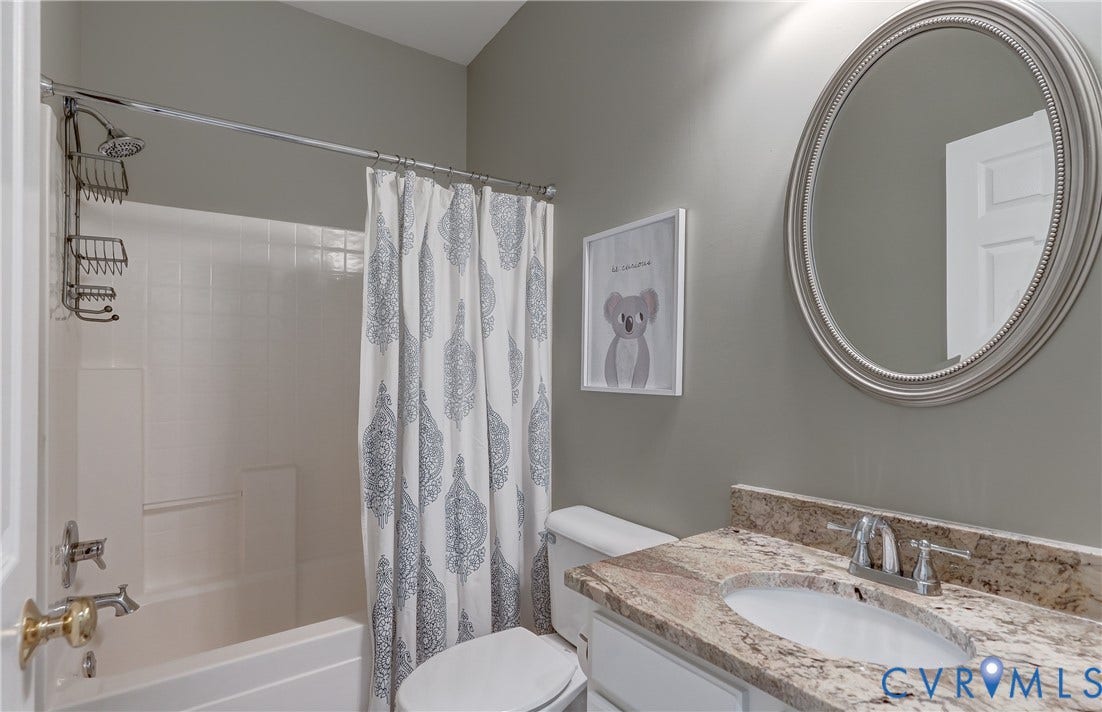 332 Rexmoor Terrace, Richmond, VA 23236 Bathroom featuring a white bathtub with tile surround, a toilet, a vanity with a granite countertop, an undermount sink, and a framed mirror