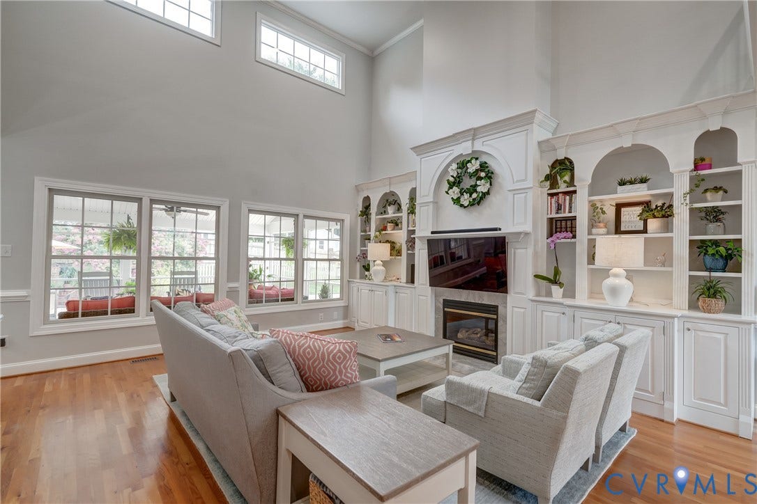 332 Rexmoor Terrace, Richmond, VA 23236 Two-story living room featuring hardwood flooring, custom built-in shelving, a fireplace with a stone surround, and multiple transom windows