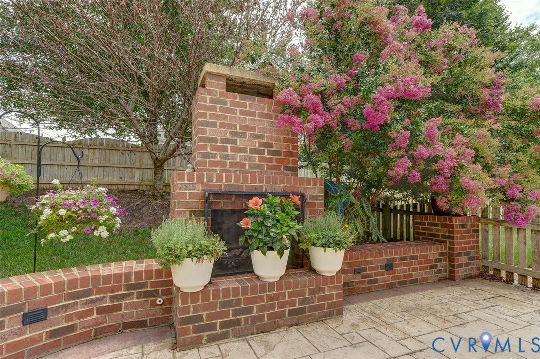 332 Rexmoor Terrace, Richmond, VA 23236 Brick outdoor fireplace with hearth, complemented by a brick retaining wall and stamped concrete patio