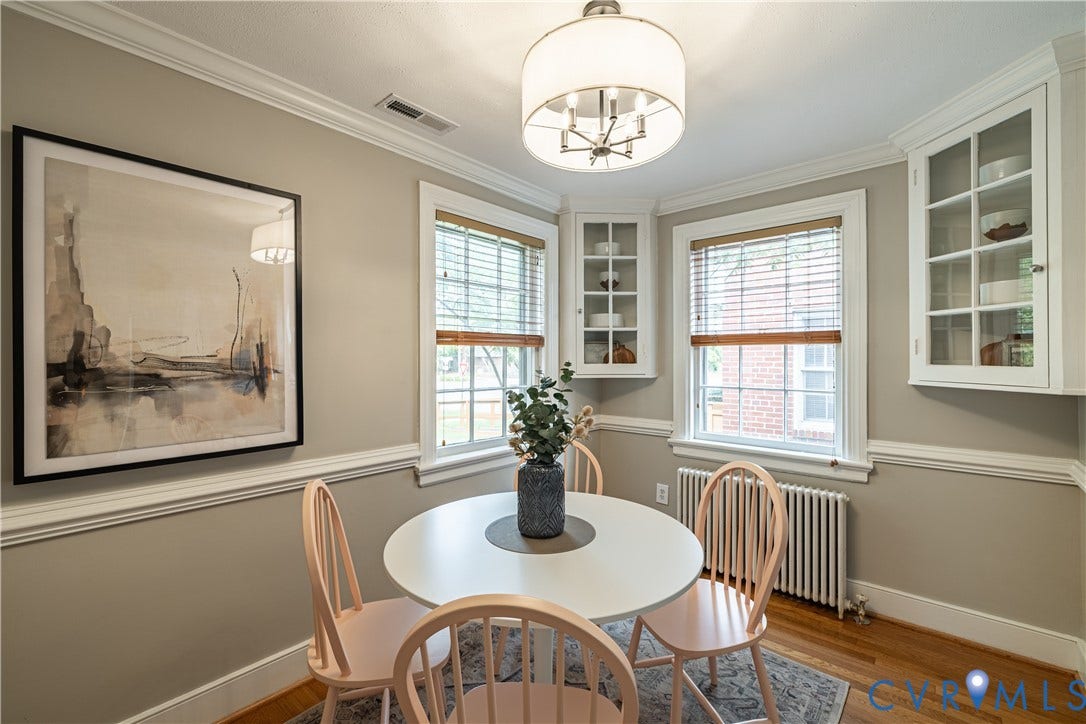 3903 Floyd Avenue, Richmond, VA 23221 Dining area featuring hardwood flooring, crown molding, a built-in corner cabinet with glass fronts, new light fixture, and two windows with blinds