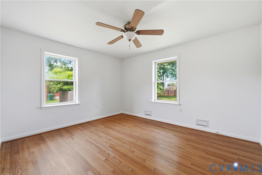 1214 Southbury Avenue, Henrico, VA 23231 Spacious room featuring wood-finish flooring, two windows with white trim, a ceiling fan with wood-tone blades, and white walls
