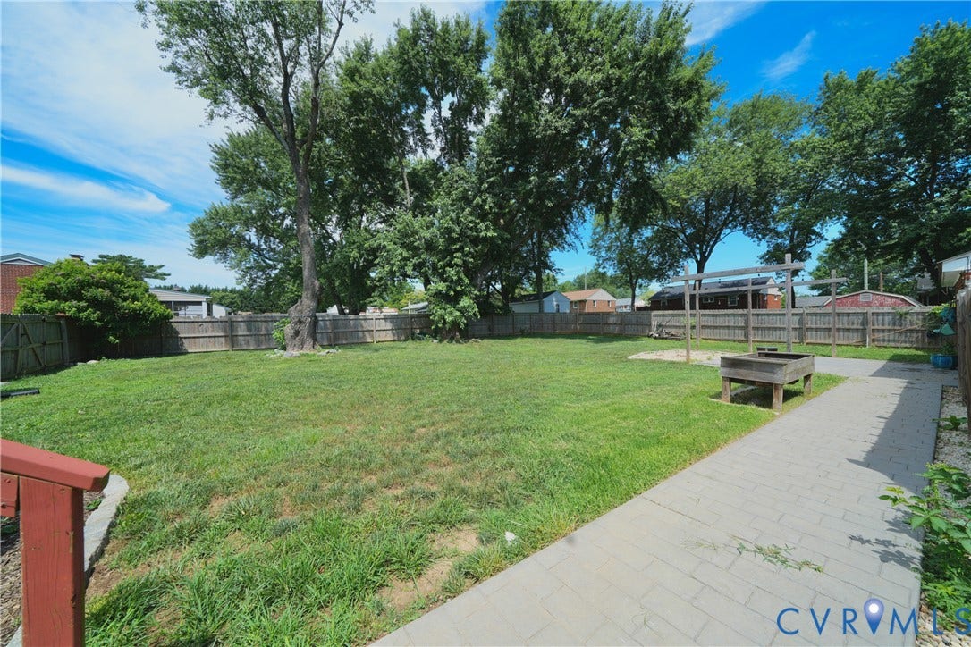 1214 Southbury Avenue, Henrico, VA 23231 Spacious backyard featuring a wood privacy fence, mature trees, and a paved walkway