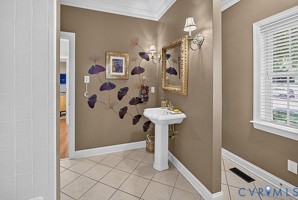 705 Lakewater Drive, Henrico, VA 23229 Pedestal sink with brass-finish faucet, framed mirror, and wall sconces