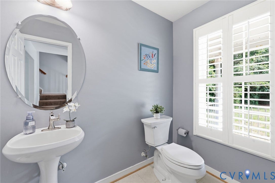 Pedestal sink with polished chrome faucet and oval, beveled-edge mirror