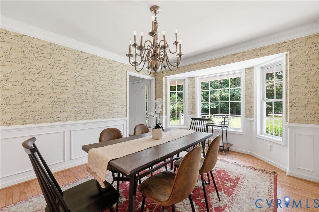 Dining area featuring wainscoting and script-patterned wallpaper