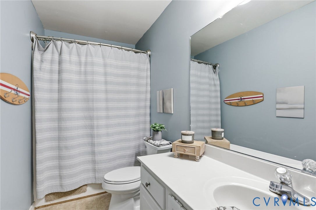 Bathroom featuring a single-sink vanity with white countertop, chrome faucet, and integrated mirror
