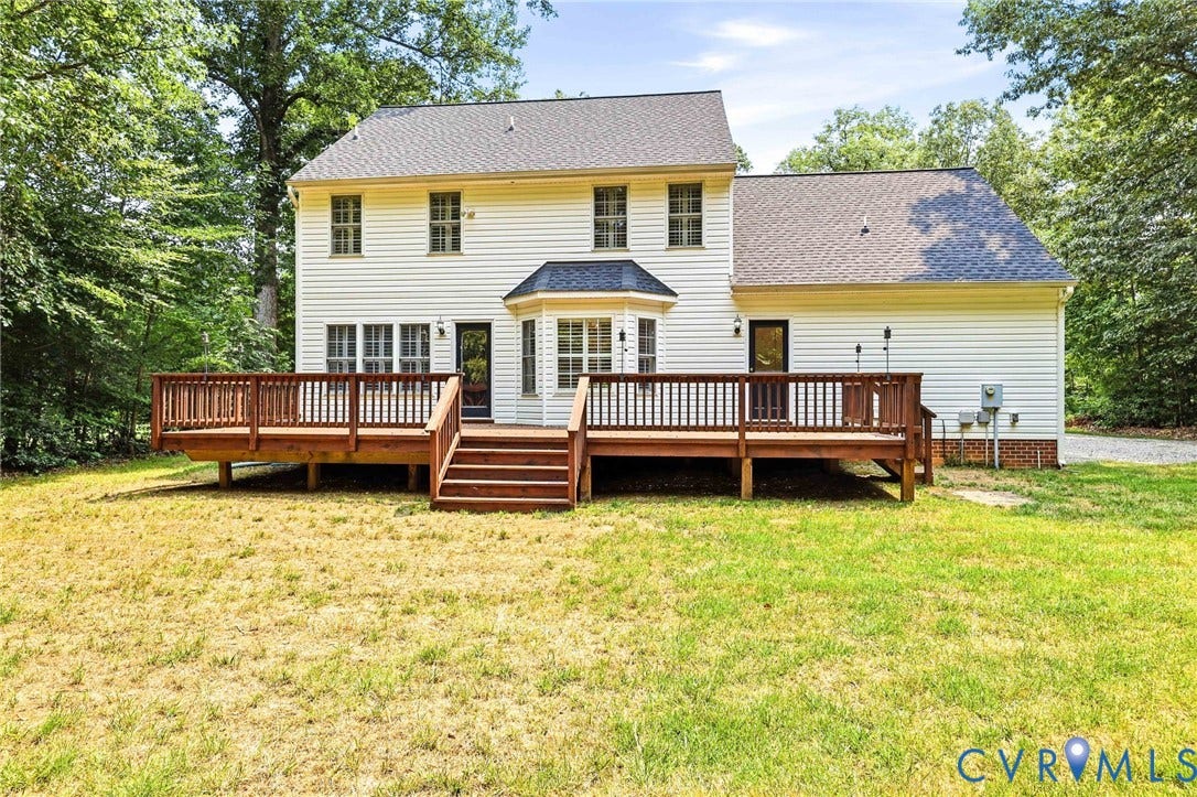 Expansive rear deck with multiple access points overlooking a private backyard framed by mature trees