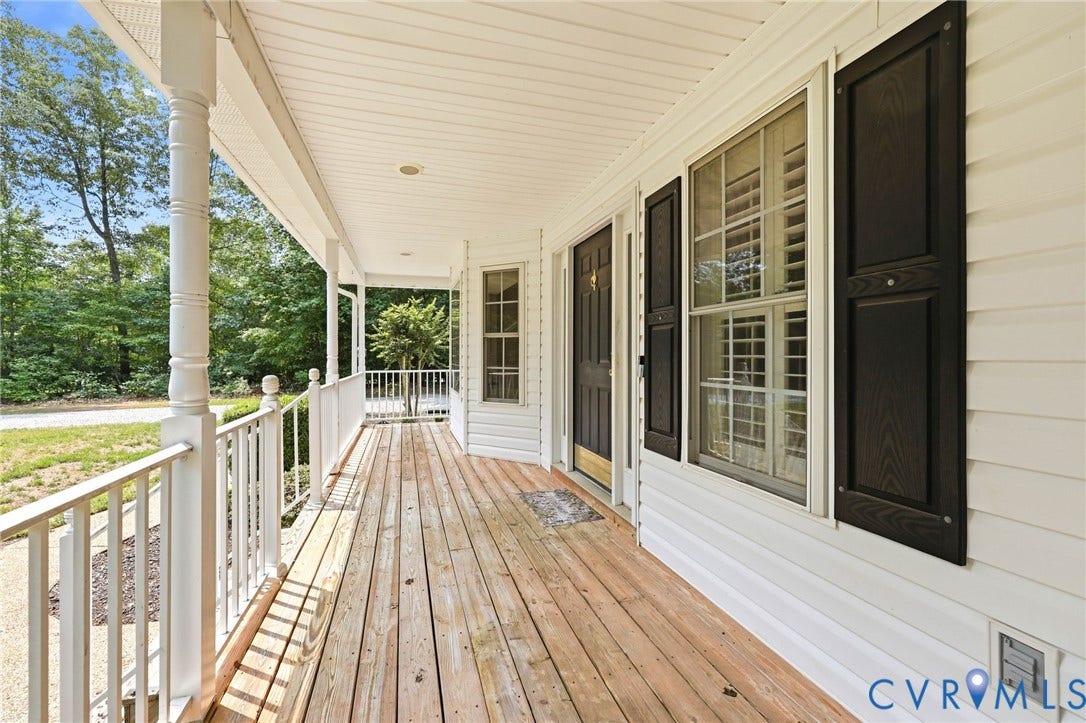 Expansive front porch featuring natural wood flooring and white railing