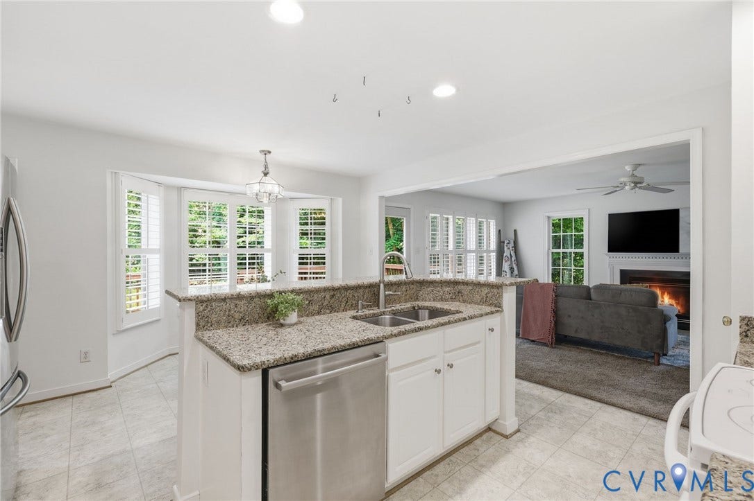 Kitchen island featuring a double-basin stainless steel sink, integrated stainless steel dishwasher, and granite countertop with a raised bar