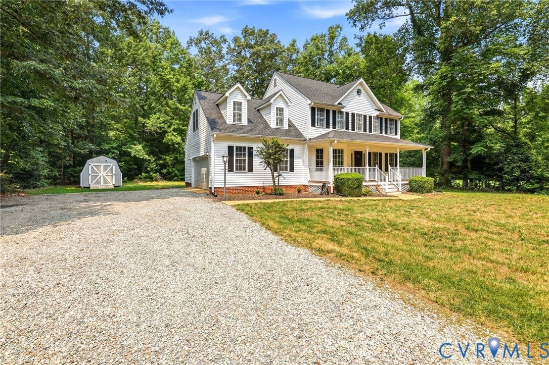 Two-story residence featuring white siding, black shutters, and a covered front porch with white columns and railings