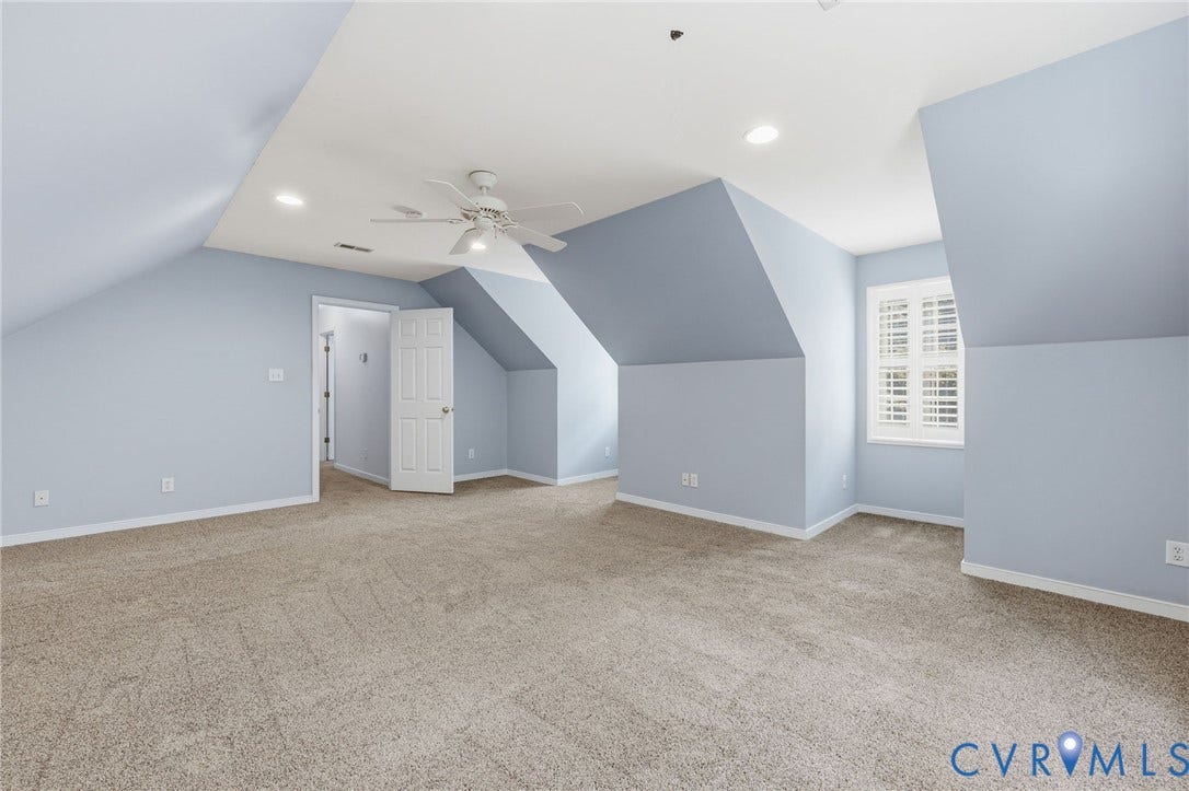 Spacious room featuring sloped ceilings, recessed lighting, and a ceiling fan