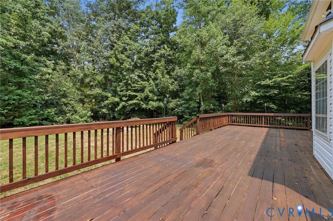 Expansive wood deck with a natural finish, surrounded by mature trees