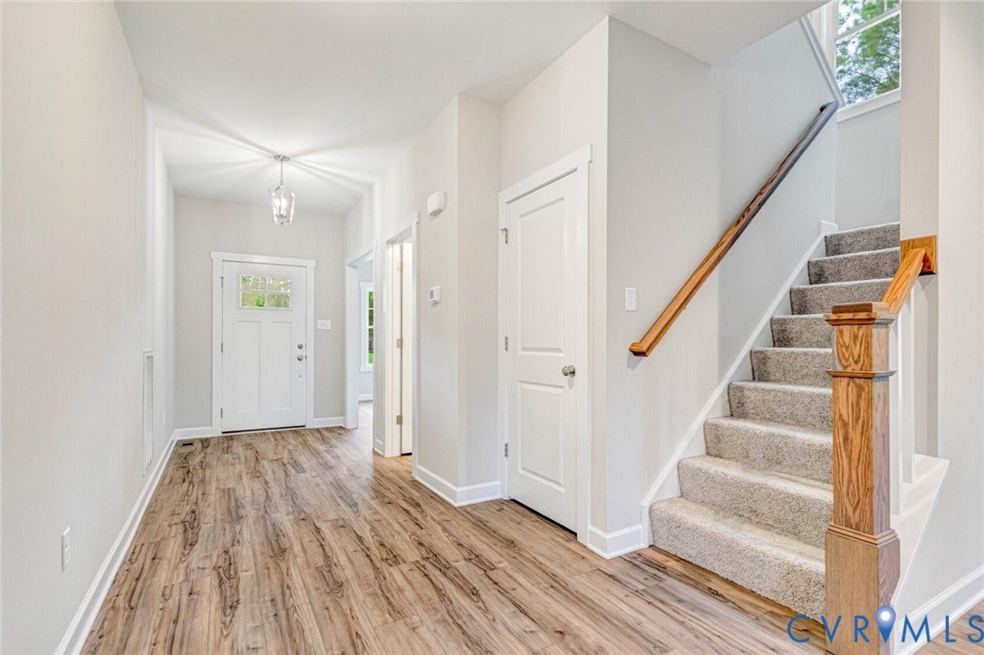 Foyer featuring wood-finish flooring, light grey walls, a white front door with upper glass paneling, and a contemporary pendant light fixture