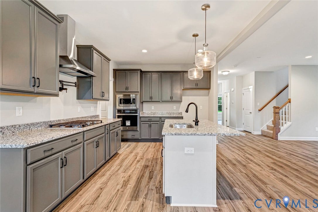 Modern kitchen featuring gray cabinetry, light-toned countertops, and wood-finish flooring