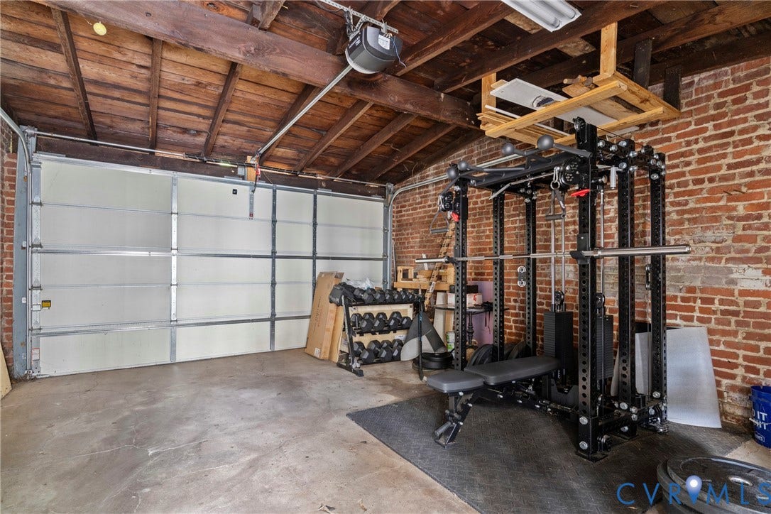 3331 W Grace Street, Monument Avenue, Richmond, VA 23221 Exposed brick wall garage featuring a concrete floor, segmented garage door, and exposed wood beam ceiling