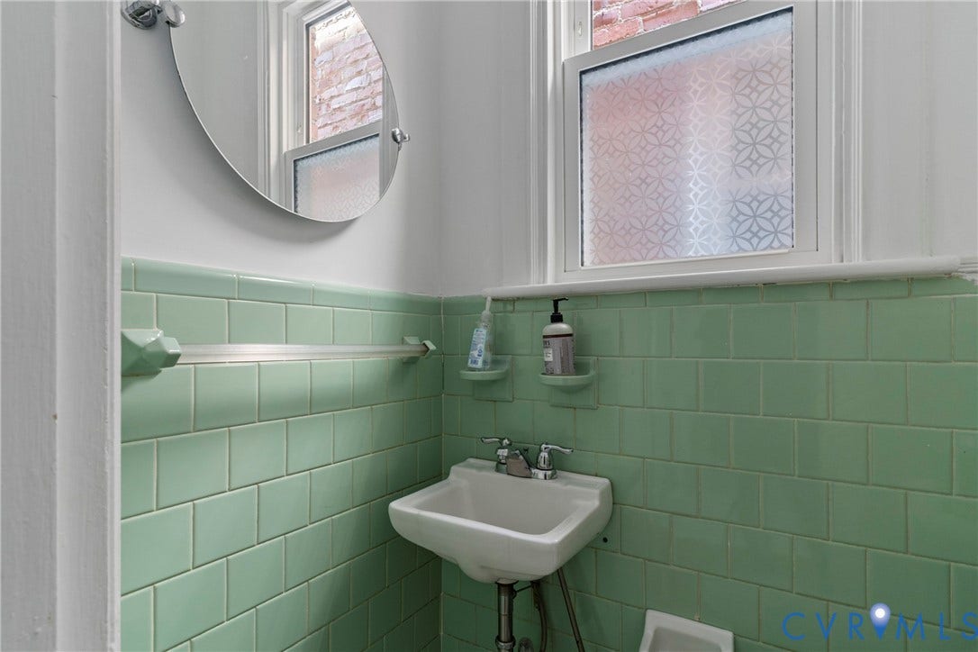 3331 W Grace Street, Monument Avenue, Richmond, VA 23221 Bathroom featuring green subway tile wainscoting, a wall-mounted sink, and a frosted window with a geometric pattern