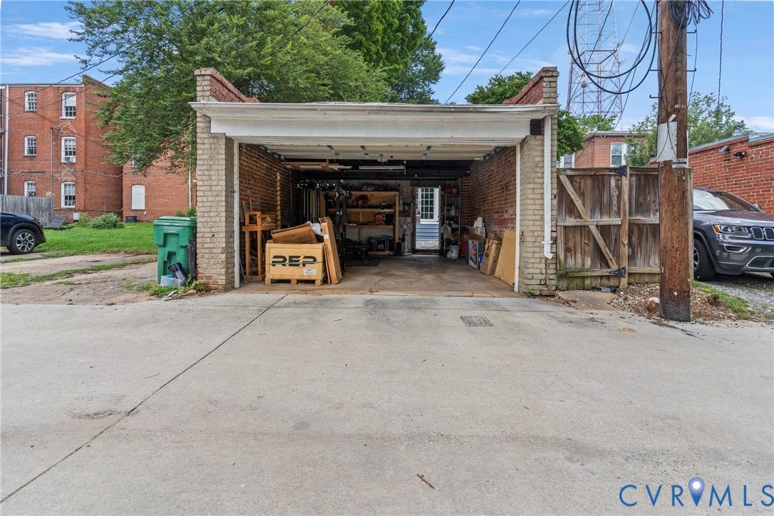 3331 W Grace Street, Monument Avenue, Richmond, VA 23221 Brick garage structure with an overhead door, concrete driveway, and a wood privacy fence