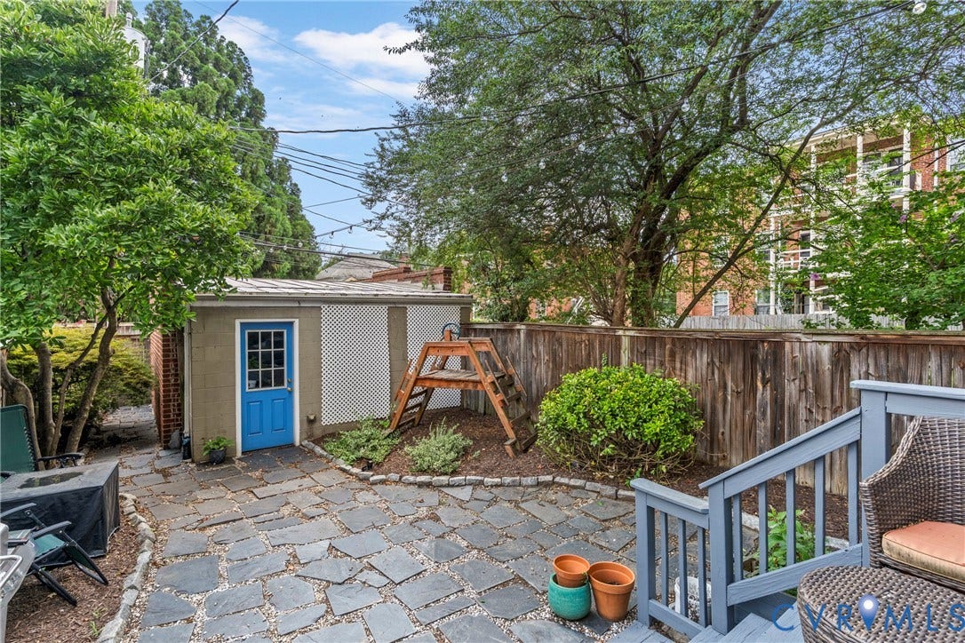 3331 W Grace Street, Monument Avenue, Richmond, VA 23221 Flagstone patio area featuring a detached storage shed with a vibrant blue door, wooden privacy fence, and established landscaping