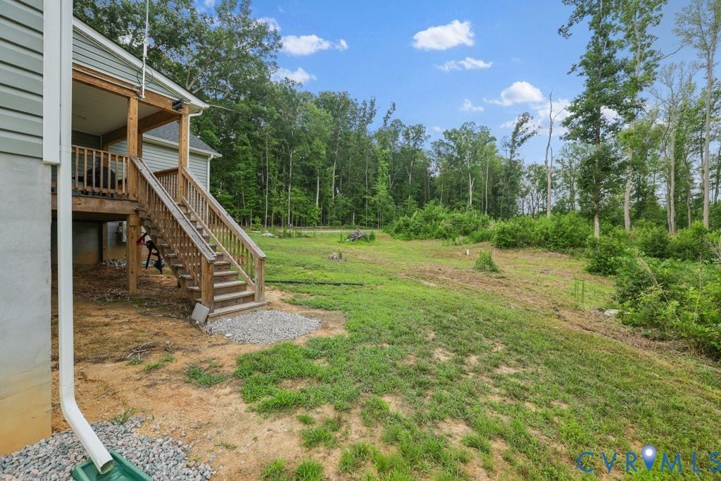 3259 Three Bridge Road, Powhatan, VA 23139 Rear elevated wood deck with stairs leading to a spacious, partially cleared yard