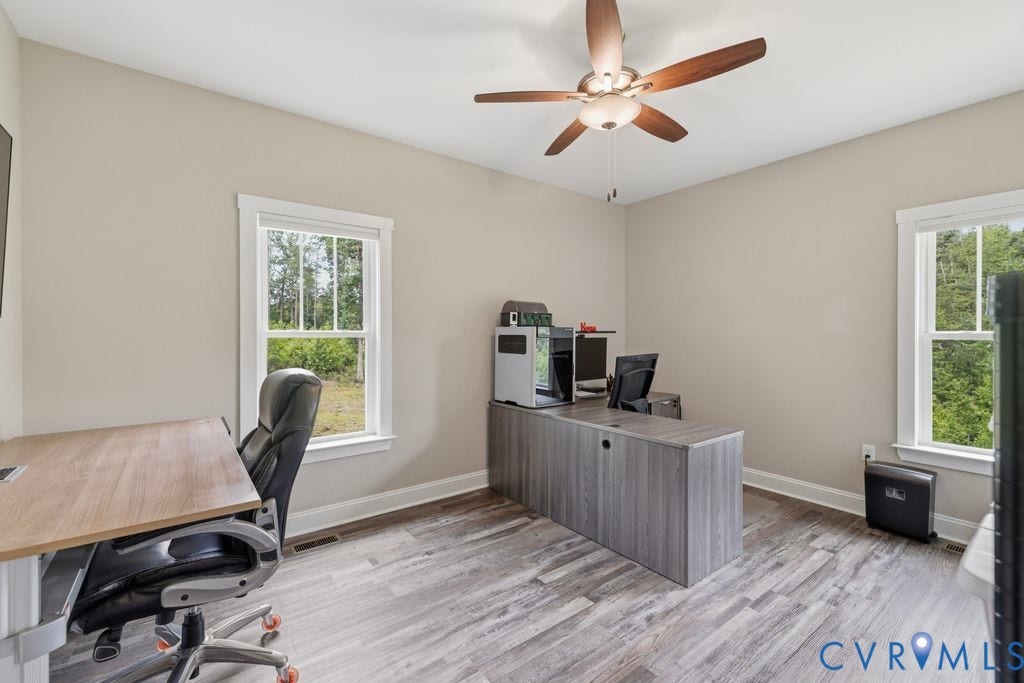 3259 Three Bridge Road, Powhatan, VA 23139 Neutral painted walls with white trim, wood-finish flooring, two large windows, and a ceiling fan with light fixture