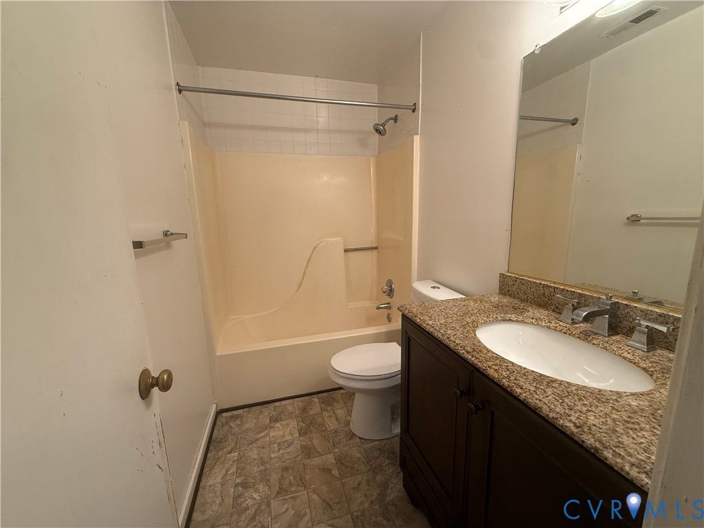 Bathroom featuring a dark wood-finish vanity with a granite countertop, undermount sink, and chrome fixtures