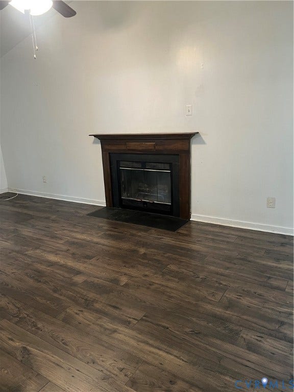 Living area featuring a dark wood-finish mantel over a fireplace with a black glass door, set against white walls