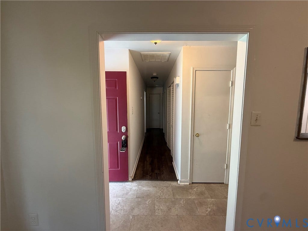 Hallway with wood-finish flooring, white paneled doors, and a distinct red-painted door