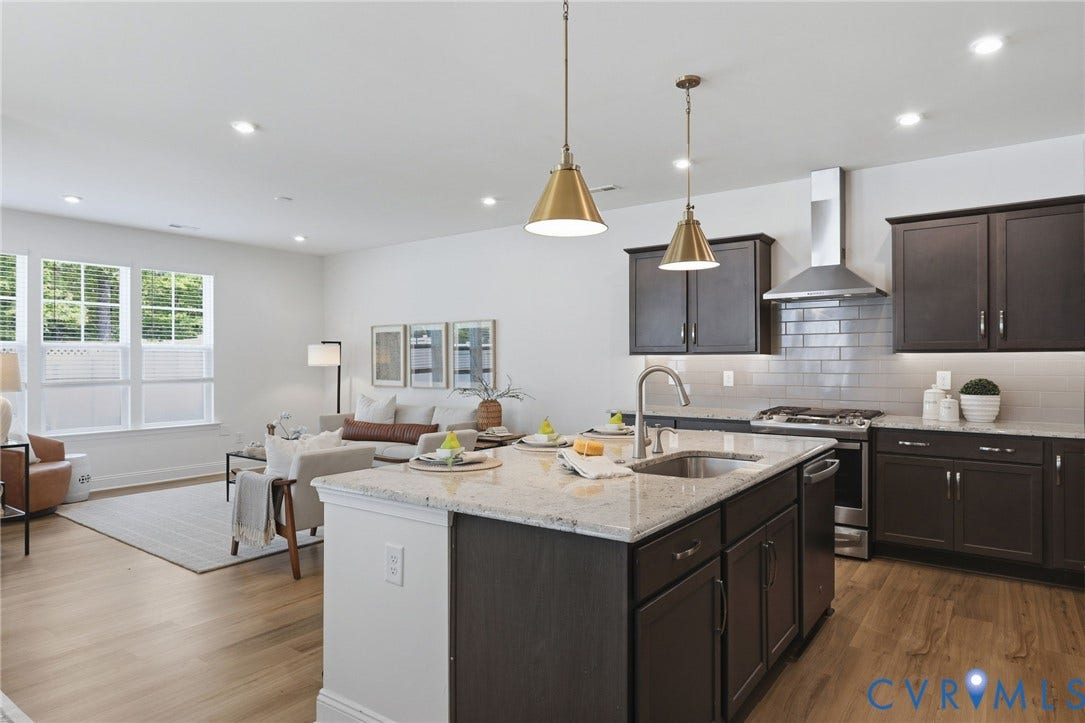 10880 Farmstead Mill Lane, Glen Allen, VA 23059 Open-concept living space featuring a kitchen island with stone countertop, stainless steel appliances, dark wood-finish cabinetry, and wood-finish flooring