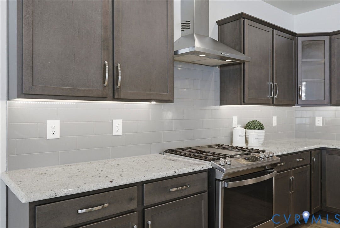 10880 Farmstead Mill Lane, Glen Allen, VA 23059 Kitchen featuring dark wood cabinetry, light-toned countertops, a stainless steel gas range, and a coordinating stainless steel range hood