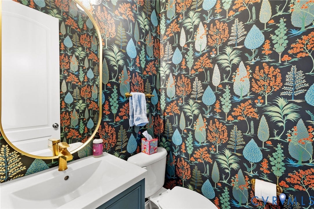 15936 Alsdell Road, Hallsley, Midlothian, VA 23112 Powder room featuring whimsical tree-patterned wallpaper, a gold-framed oval mirror, a white vanity with a gold-finish faucet, and a toilet