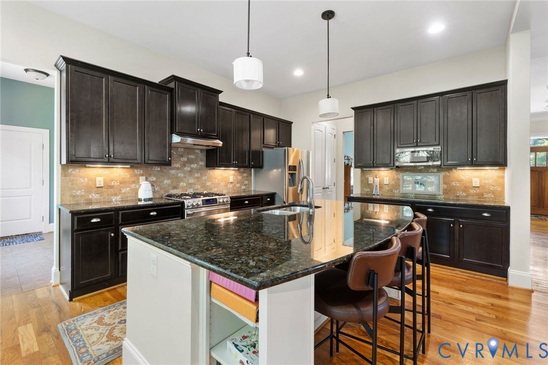 15936 Alsdell Road, Hallsley, Midlothian, VA 23112 Gourmet kitchen featuring a large island with an undermount sink, dark wood cabinetry, stainless steel appliances, a tile backsplash, and wood-finish flooring