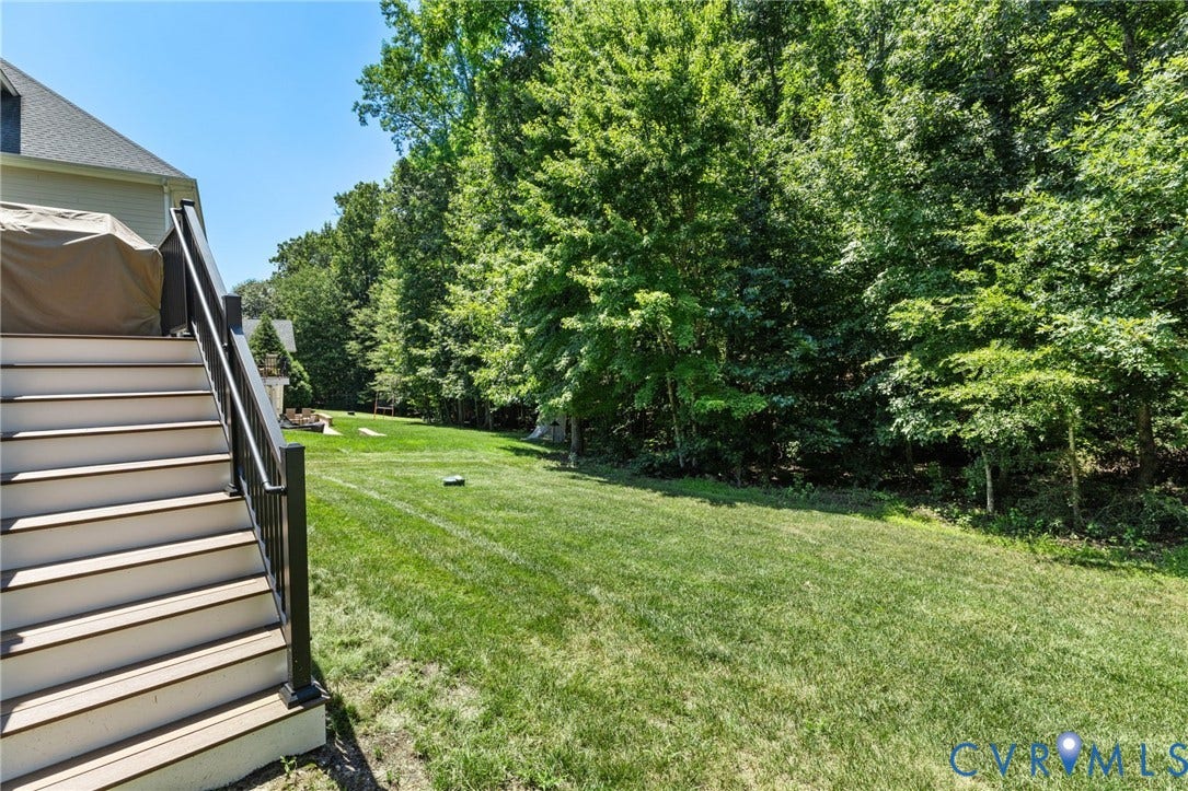 15936 Alsdell Road, Hallsley, Midlothian, VA 23112 Expansive green lawn framed by mature trees, featuring a multi-level deck with black railings and light-colored treads