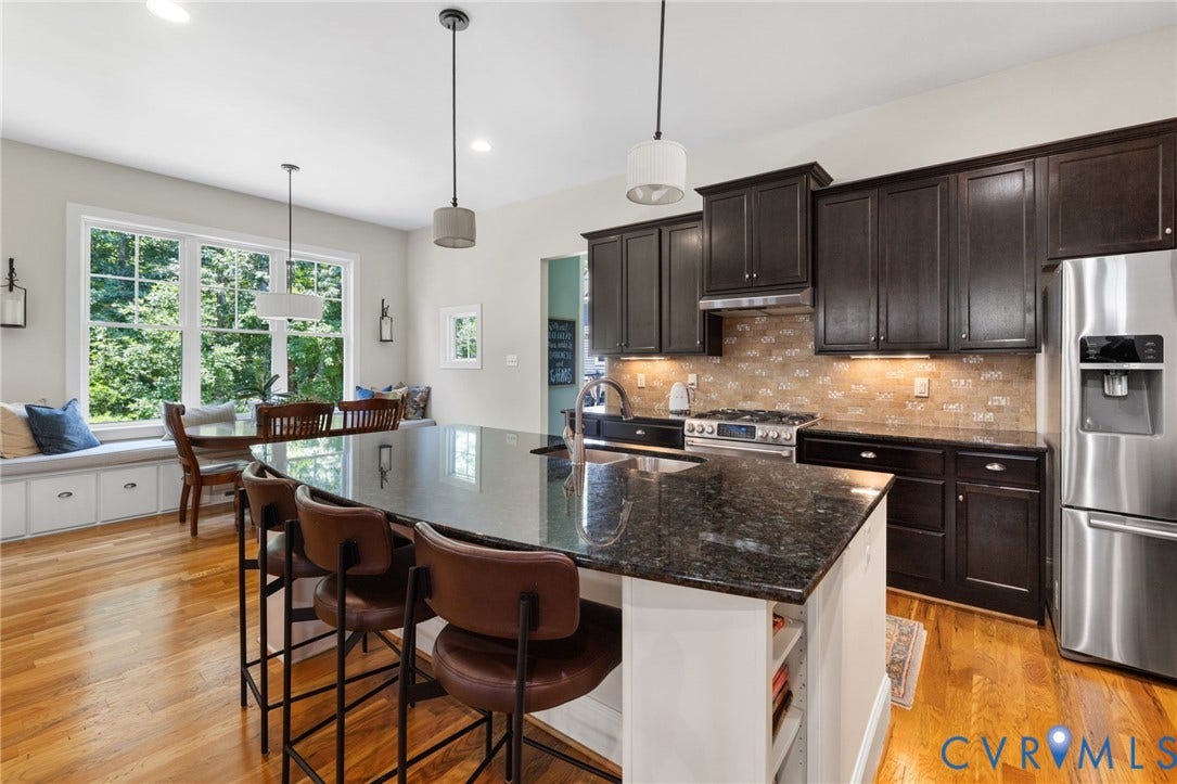15936 Alsdell Road, Hallsley, Midlothian, VA 23112 Gourmet kitchen featuring a large island with dark stone countertop, full-height dark cabinetry, stainless steel appliances, and a tile backsplash