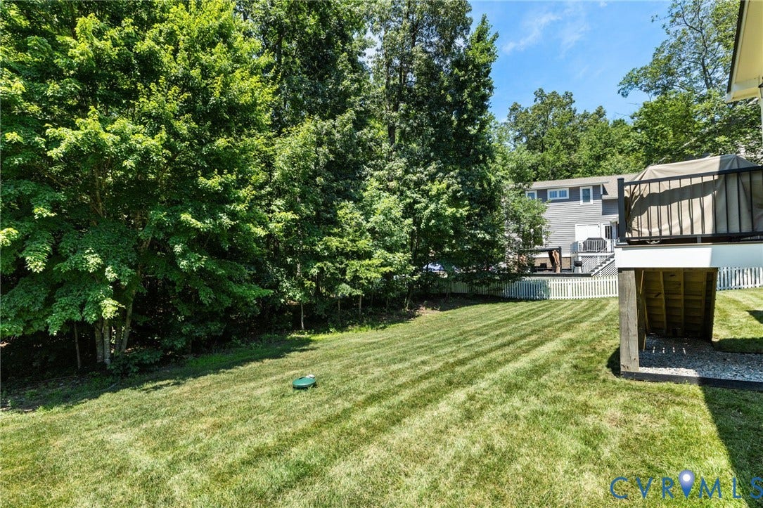 15936 Alsdell Road, Hallsley, Midlothian, VA 23112 Expansive backyard featuring a manicured lawn, white picket fencing, and mature trees