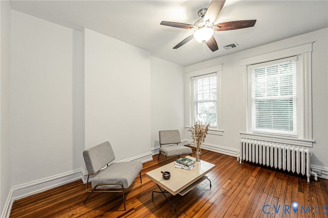 Hardwood flooring throughout featuring white baseboards, window trim, and a ceiling fan with integrated lighting