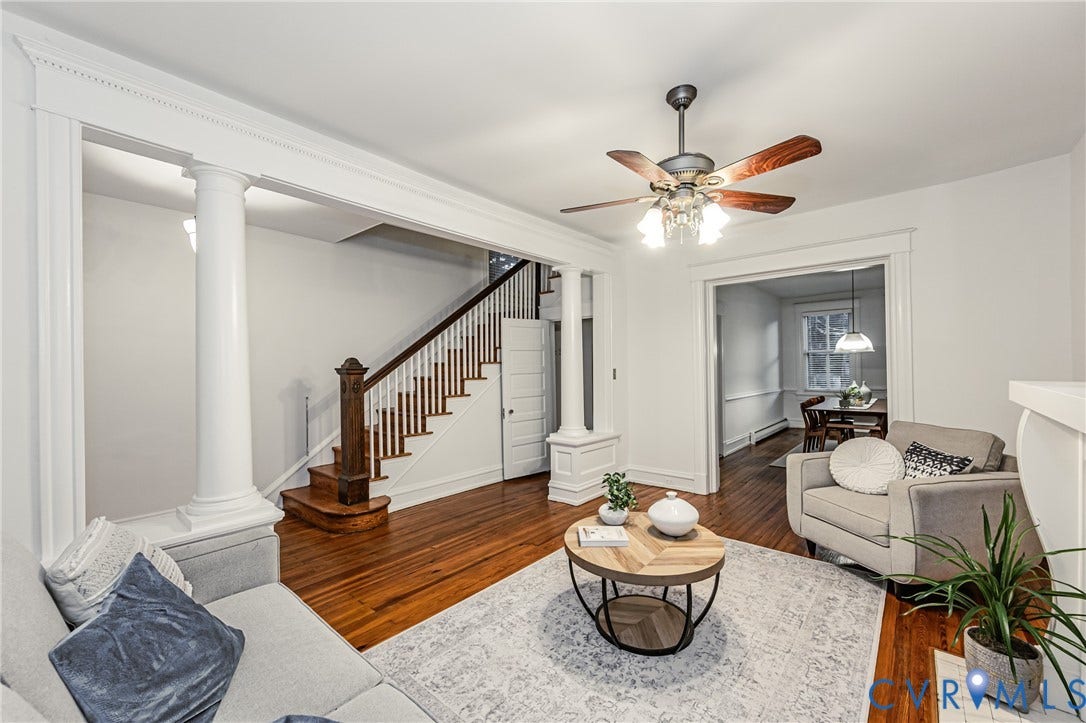 Hardwood flooring throughout the main living area, featuring a decorative ceiling fan and elegant white columns