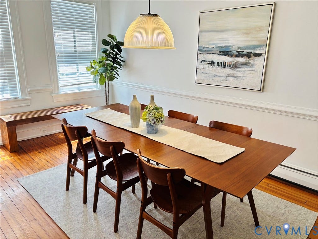 Formal dining space featuring wood flooring, white paneled walls, and a contemporary pendant light fixture
