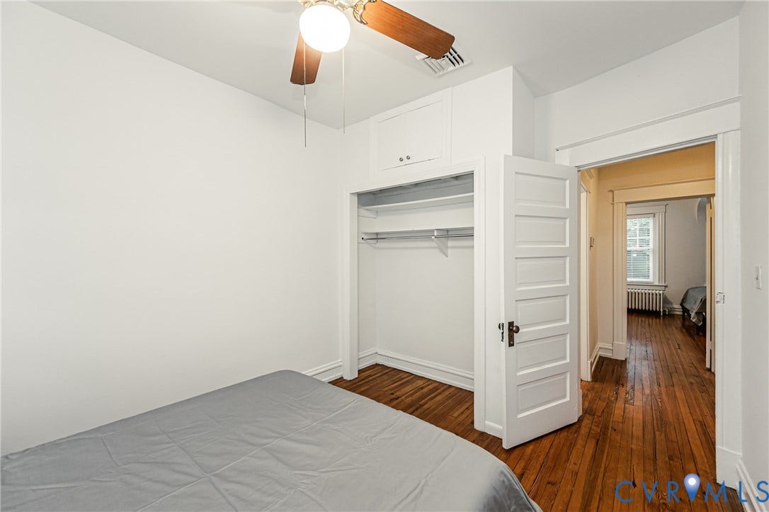 Room featuring wood-finish flooring, a ceiling fan with integrated lighting, and white walls